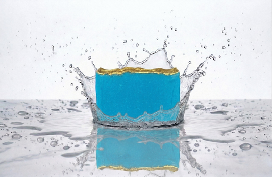 Turquoise Soap with gold top, white background, the soap is making a big water splash
