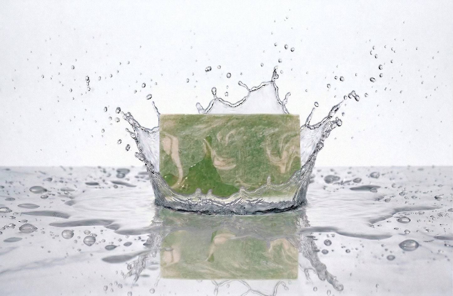 Green and cream coloured swirled bar of soap on a white background splashing in  water